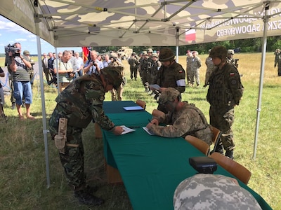 U.S. Army Col. Phil Brooks, seated, commander of the 1st Armored Brigade Combat Team, 3d Infantry Division, Fort Stewart, Ga., signs a transfer of authority agreement during an opening ceremony for Exercise Anakonda 2016 at the Drawsko Pomorskie Training Area, Poland, June 6. Exercise Anakonda 2016 is a Polish-led, joint multinational exercise taking place throughout Poland June 7-17. The exercise involves approximately 31,000 participants from more than 20 nations. Exercise Anakonda 2016 is a premier training event for U.S. Army Europe and participating nations and demonstrates the United States and partner nations can effectively unite under a unified command while training on a contemporary scenario. (U.S. Army photo by Timothy L. Hale) (Released)