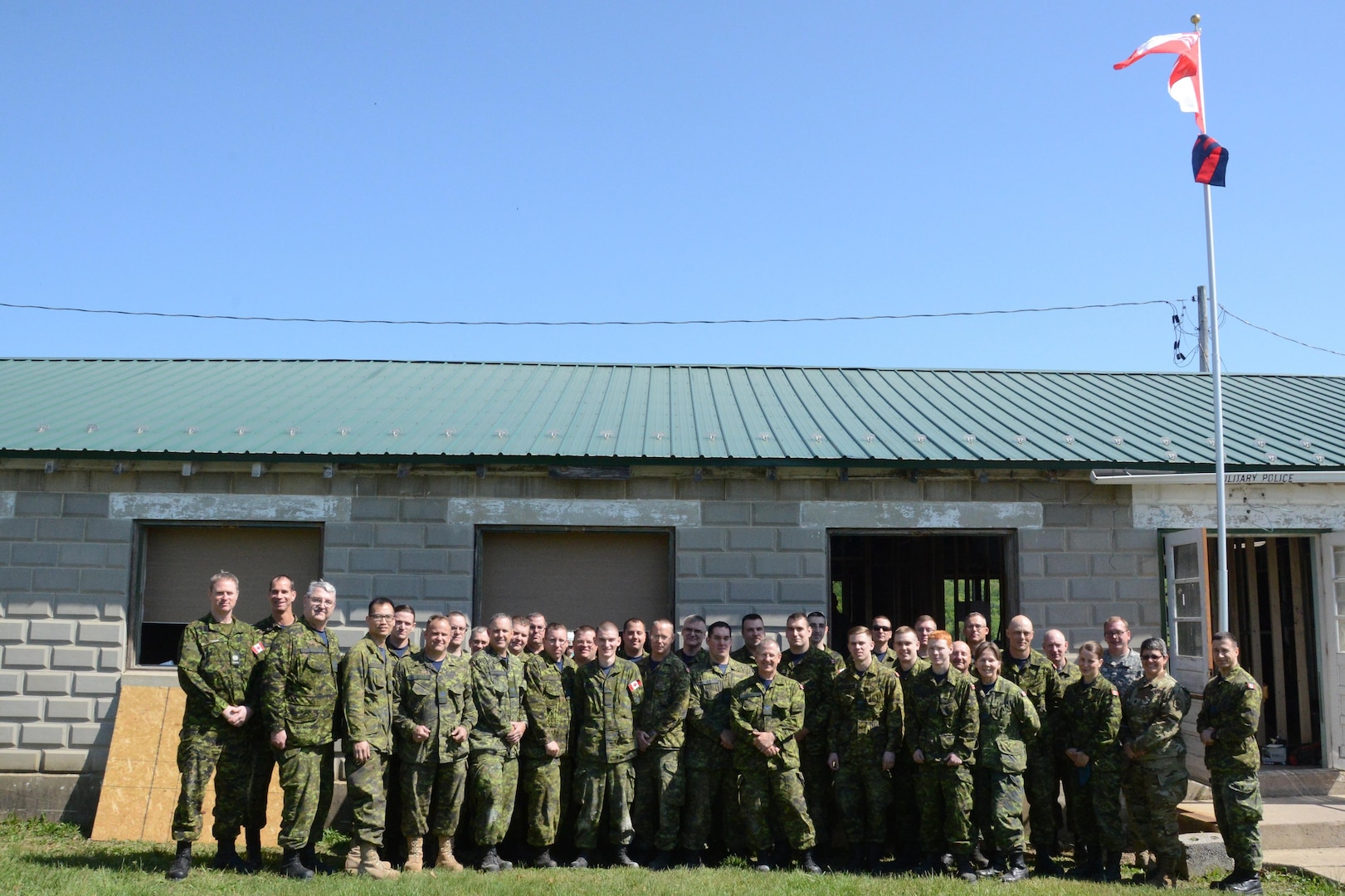 Canadian and American forces gather for a group shot in front of the building the Canadian troops helped to renovate. The troops were here for several weeks as part of a partnership program that offers U.S. and Canada engineers to train together.