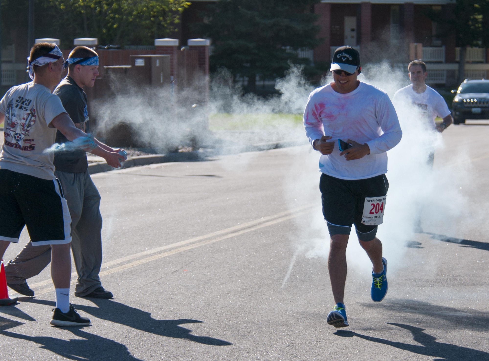 Air Force Sergeants Association Chapter 1178 volunteers drench Airman 1st Class Allan Grove, 90th Force Support Squadron, in colored chalk powder as he runs through one of the many color-throwing spots along the Color Run on F.E. Warren Air Force Base, Wyo., June 4, 2016. Runners finished the race covered in multicolored-chalk powder. (U.S. Air Force photo by Senior Airman Jason Wiese)