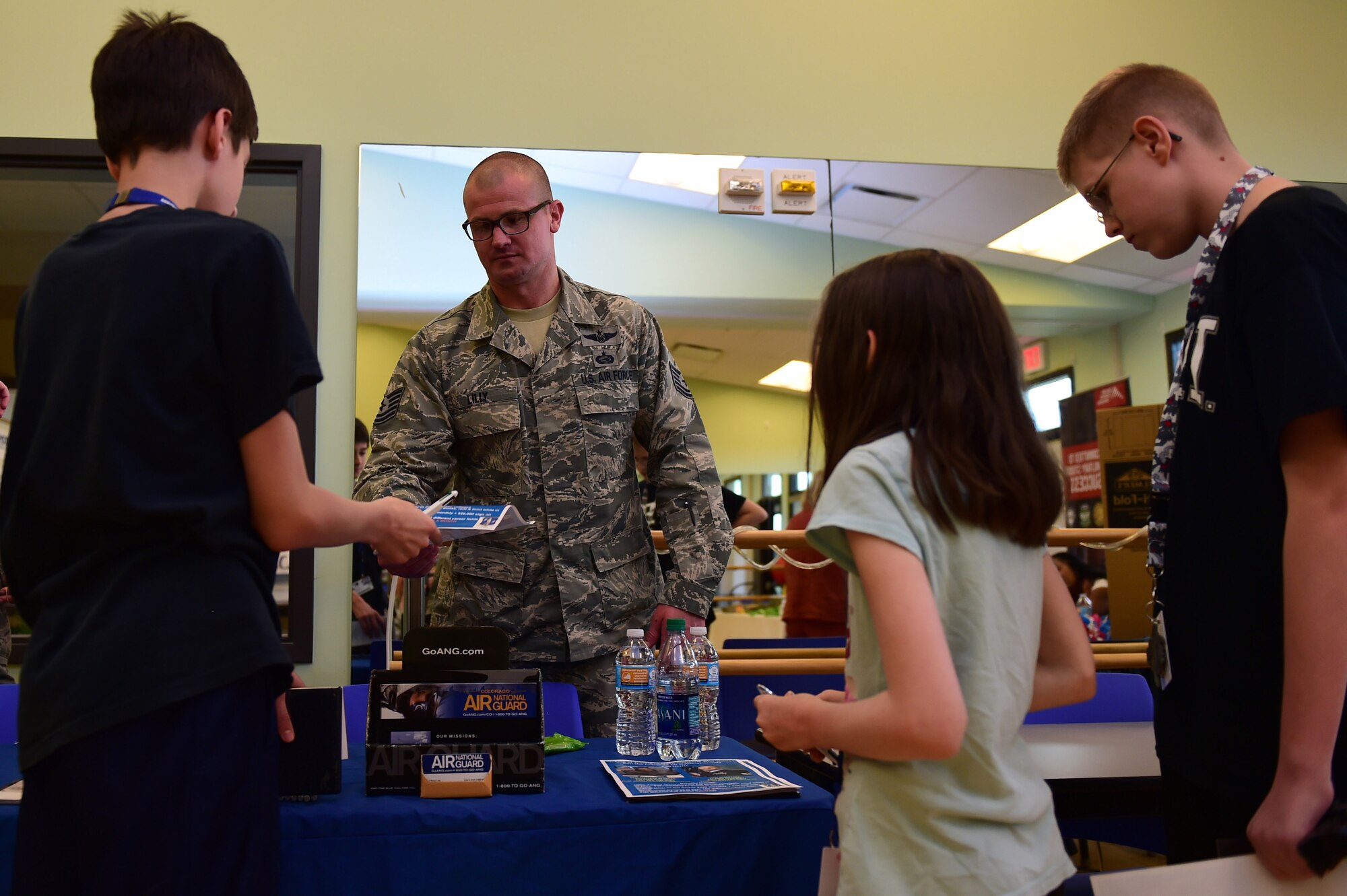 Tech. Sgt. Brian Lilly, Colorado Air National Guard 140th Wing recruiter, speaks with children June 3, 2016, during a College and Career Expo at the youth center on Buckley AFB, Colo. Members from the ANG spoke with Buckley AFB youth, along with providing informational pamphlets, about the educational and career benefits that the Guard offers. (U.S. Air Force photo by Airman 1st Class Gabrielle Spradling/Released)