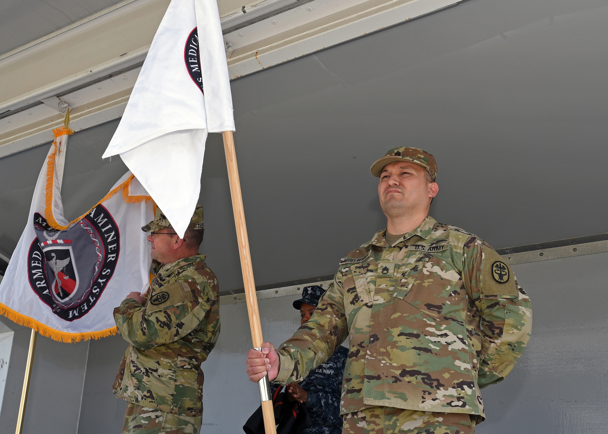 Army Col. Ladd Tremaine, Armed Forces Medical Examiner System director, left, and Army Staff Sgt. Jaime Torres Mendoza, Post Mortem/Human Performance Forensic Toxicology Department NCO in charge, display the new official seal during an unveiling ceremony May 26, 2016, at AFMES on Dover Air Force Base, Del. This follows the changing of the seal by Tremaine moments earlier. (U.S. Navy photo/Mass Communication Specialist 3rd Class Jonteil Johnson)