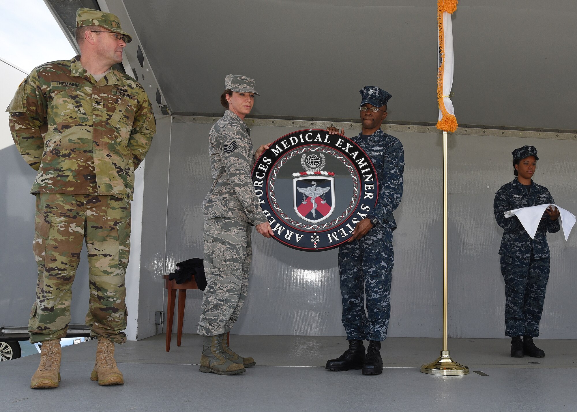 Service members from the Armed Forces Medical Examiner System uncover the new official seal during an unveiling ceremony May 26, 2016, at AFMES on Dover Air Force Base, Del. AFMES personnel celebrated the historic event as a way to honor the old seal while embracing the new seal. (U.S. Navy photo/Mass Communication Specialist 3rd Class Jonteil Johnson)