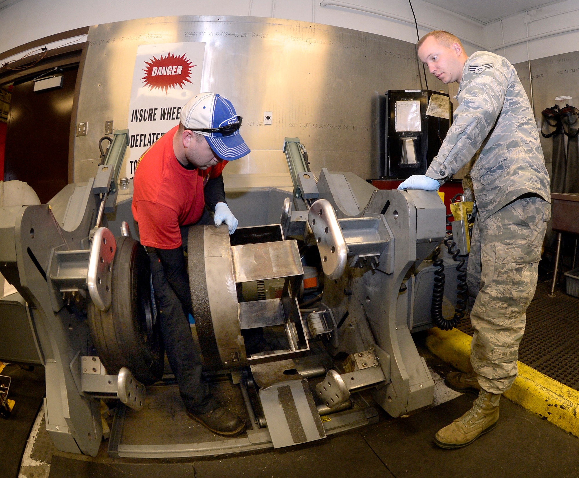 Tech. Sgt. James Speicher, an Air Reserve Technician from the 419th Maintenance Squadron, and Senior Airman Joseph Sprowls, 388th Maintenance Squadron, install a newly fabricated compressing component to a legacy tire-changing machine in the wheel and tire shop at Hill Air Force Base, May 20. The fabricated component – a tire bead breaker – is necessary for removing the F-35 tires from their rims. (U.S. Air Force photo by Todd Cromar)