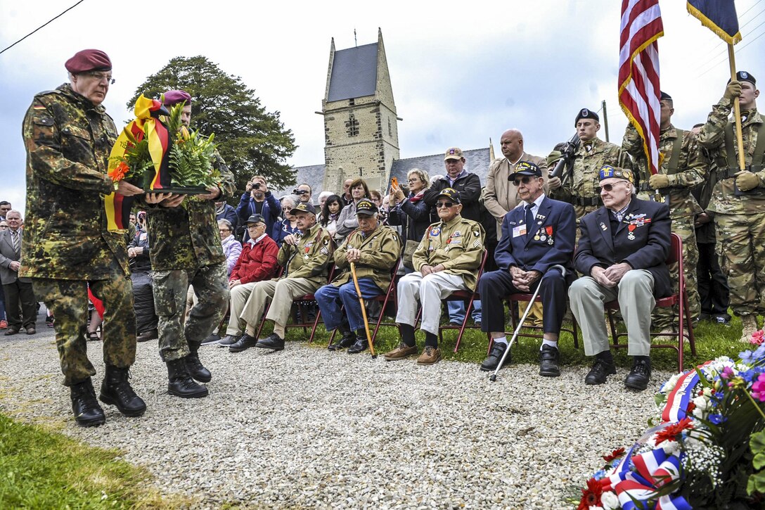German veterans prepare to lay a wreath at the memorial dedicated to Army veterans Kenneth Moore and Robert Wright in Angoville-au-Plain, France, June 4, 2016. Air Force photo by Staff Sgt. Timothy Moore