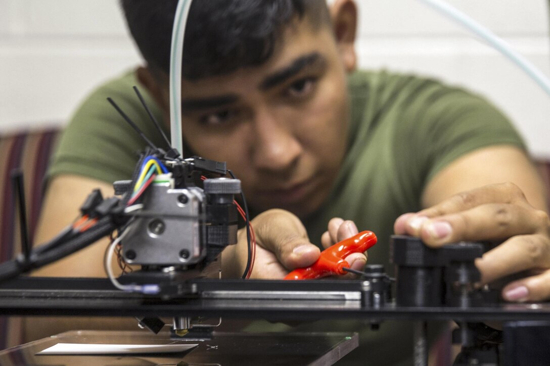 A Marine makes small adjustments to a 3D printer before loading a design during a class at Marine Corps Base Camp Lejeune, N.C., June 2, 2016. Additive manufacturing, or 3D printing, allows Marines to produce parts quickly with exact specifications and at almost any location. Marine Corps photo by Cpl. Justin Updegraff