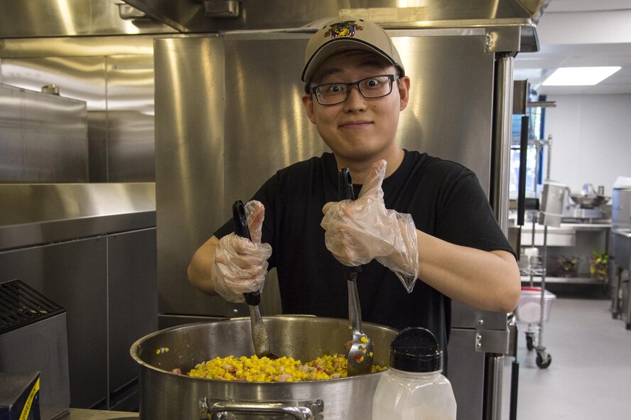 U.S. Air Force Airman 1st Class Chen Liang, 23d Force Support Squadron food service apprentice, puts the finishing touches on his dish during a Top Chef Competition, June 3, 2016, at Moody Air Force Base, Ga. Liang made skillet-fried corn as the vegetable for the competition. (U.S. Air Force photo by Airman 1st Class Janiqua P. Robinson/Released)