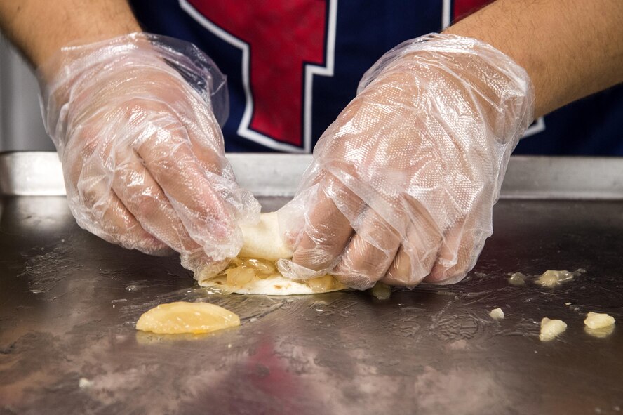 U.S. Air Force Senior Airman Christopher Windley, 23d Force Support Squadron food service apprentice, rolls an apple chimichanga during a Top Chef Competition, June 3, 2016, at Moody Air Force Base, Ga. Windley fried the apple pie centered chimichanga, coated it with cinnamon sugar and a drizzled caramel on top. (U.S. Air Force photo by Airman 1st Class Janiqua P. Robinson/Released)