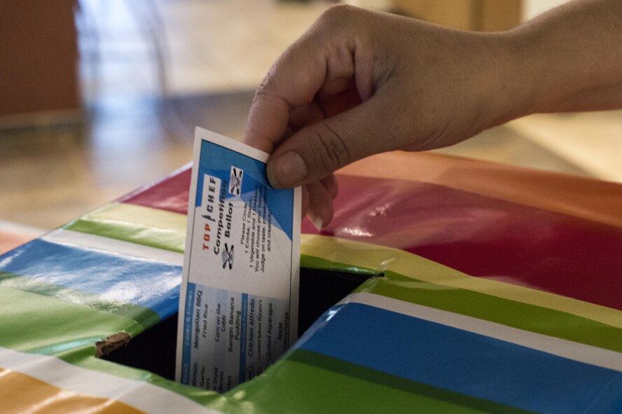 A participant casts a vote for their favorite team during a Top Chef Competition, June 3, 2016, at Moody Air Force Base, Ga. Their selection was based on the food’s taste, creativity, and presentation. (U.S. Air Force photo by Airman 1st Class Janiqua P. Robinson/Released)