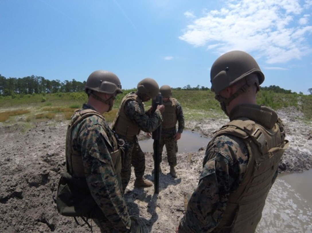 On May 26, 2016 Second Lieutenant Aaron Graham, a Marine attached to Combat Engineer Officer Course 5-16 (CEO 5-16); drives an engineer stake into the ground to place a shape charge on it, to ultimately produce a better effect. Shape charges use a cone shape to magnify the explosive power of C4. From left to right are Gunnery Sergeant John Cheze, an instructor with Combat Engineer Instruction Company, and CEO 5-16 students Second Lieutenants Aaron Graham, Brock Yackey, and Nicholas Downey.  
