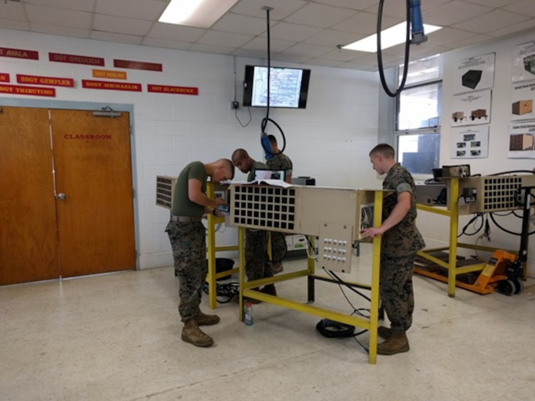 Privates First Class Christophe Martz (left) and Landon Stahly (right), Marines attached to Basic Refrigeration and Air Conditioning Technician course 3-16 (BRACT 3-16);  use their schematics and the actual equipment as the instructor guides them in a practical application on the electrical schematic for the Small Field Refrigeration System (SFRS).

