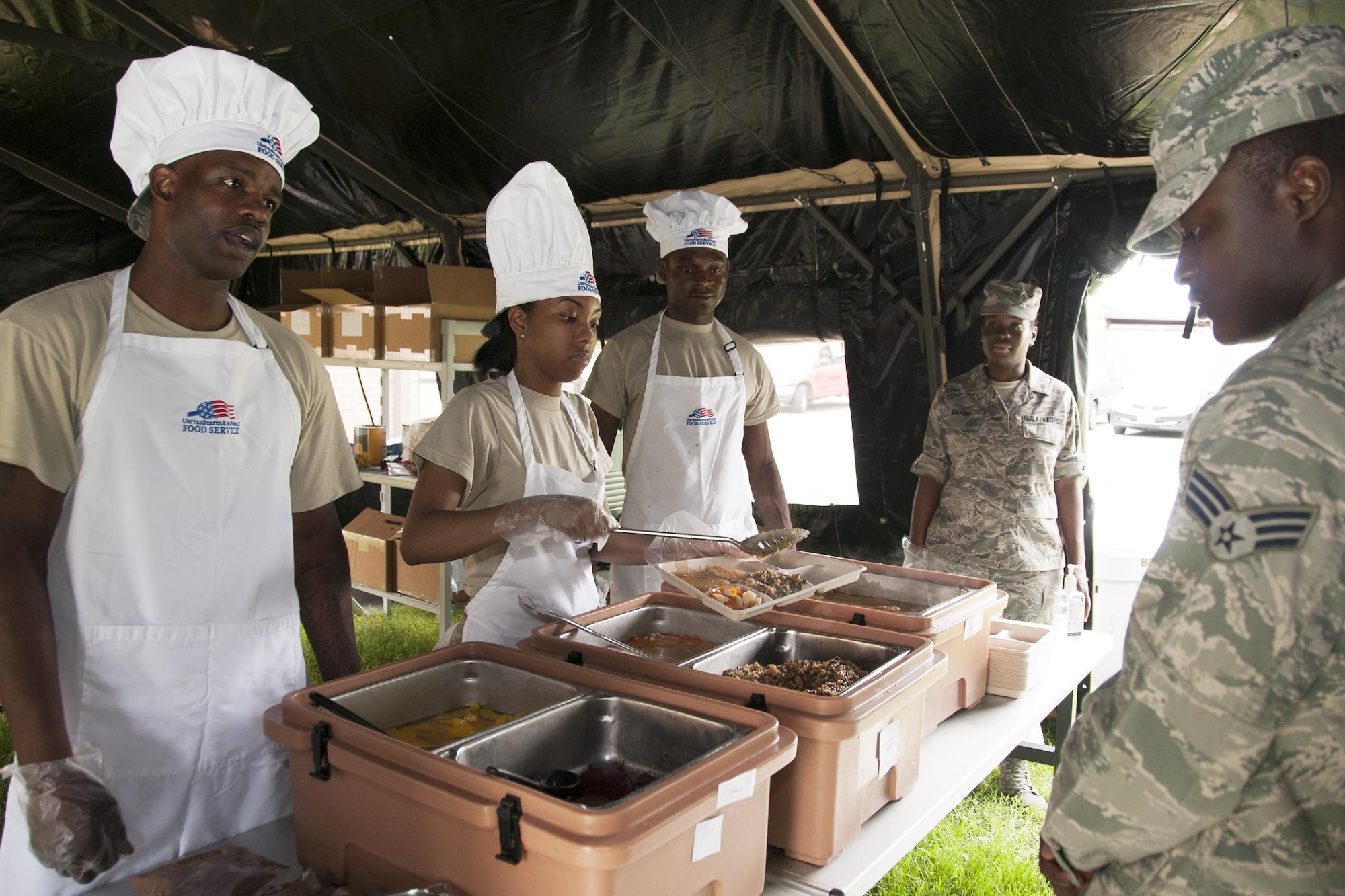 Members of the 459th Force Support Squadron food services section serve hot meals to Airmen out of a Single Pallet Expeditionary Kitchen as part of a Sustainment Bed Down of Forces exercise on Joint Base Andrews, Md., June 2, 2016. The exercise simulates Airmen deploying as advance echelon and follow-on teams into a bare base, where they stand up food, lodging, fitness, recreation and mortuary services prior to the arrival of tenant forces.  (U.S. Air Force photo/Staff Sgt. Kat Justen)