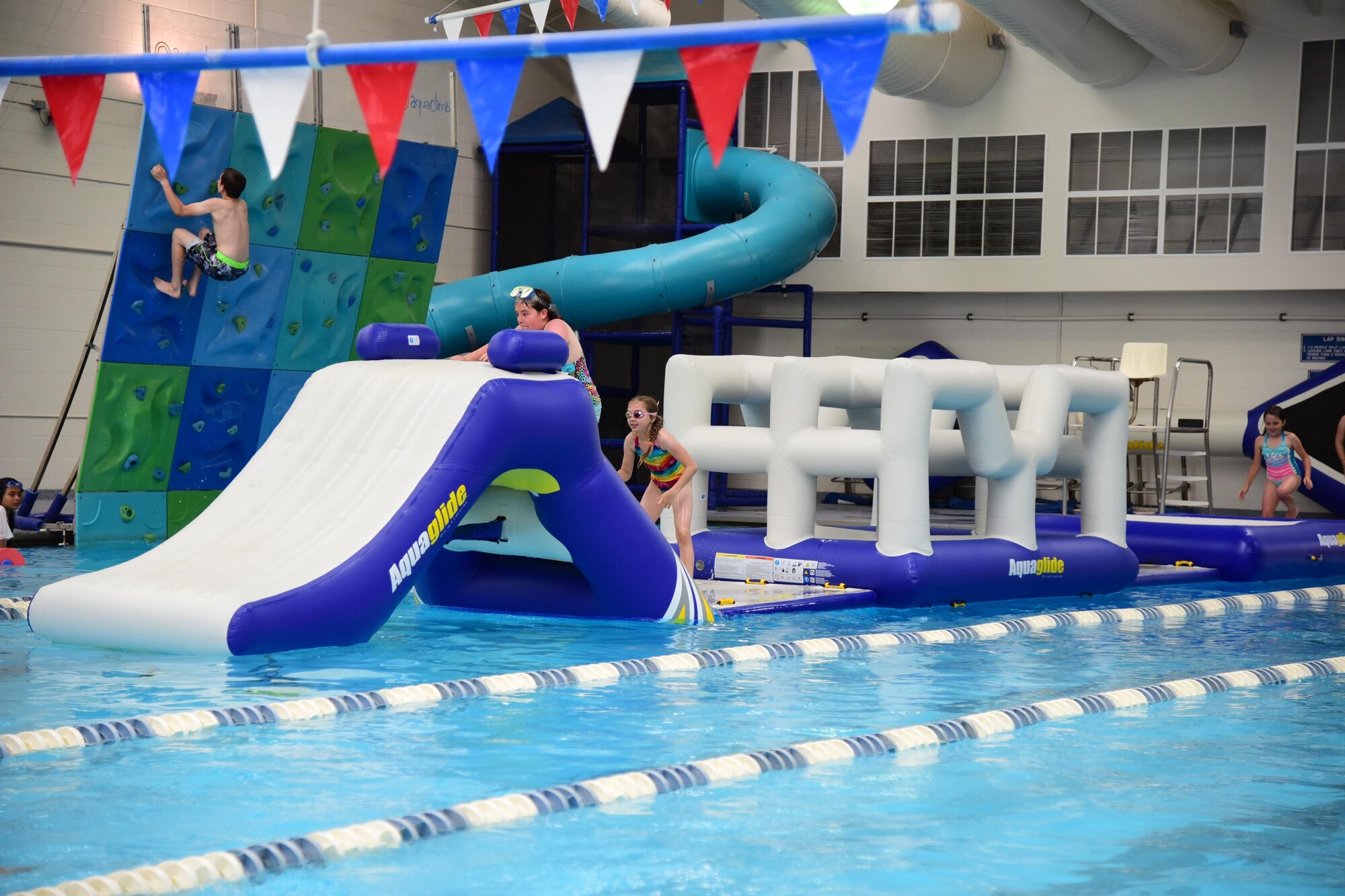 Children of Team Pete enjoy their first day in the newly renovated Peterson Air Force Base, Colo., Aquatic Center on June 6, 2016. New features include scampering across an inflatable obstacle course or using the pools climbing wall. (U.S. Air Force photo by Staff Sgt. Amber Grimm)