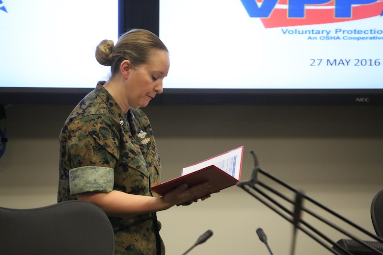 Navy Cmdr. Amy Varney recites an award during a Voluntary Protection Program Gold status achievement ceremony at Marine Corps Air Station Cherry Point, N.C., May 27, 2016. Six departments were among the first to achieve Gold status within MCAS Cherry Point VPP. Gold status is achieved when all safety protocols implemented by the VPP are completed and maintained. Some of those requirements involve monthly supervisor inspections, achieving 90-percent medical surveillance or higher, completing VPP passports and completing Occupational Safety and Health Administration training. Varney is the safety manager with the air station. (U.S. Marine Corps photo by Cpl. N.W. Huertas/ Released) 