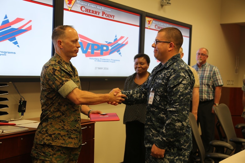 Col. Chris C. Pappas III awards departments during a Voluntary Protection Program Gold status achievement ceremony at Marine Corps Air Station Cherry Point, N.C., May 27, 2016. Six departments were among the first to achieve Gold status within MCAS Cherry Point VPP. Gold status is achieved when all safety protocols implemented by the VPP are completed and maintained. Some of those requirements involve monthly supervisor inspections, achieving 90-percent medical surveillance or higher, completing VPP passports and completing Occupational Safety and Health Administration training. Pappas is the air station commanding officer.  (U.S. Marine Corps photo by Cpl. N.W. Huertas/ Released)