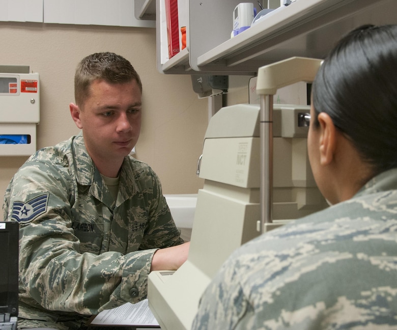 Staff Sgt. Alex Larson, 90th Medical Operations Squadron flight and operations medicine technician, demonstrates the eye examination process with the help of a coworker June 1, 2016, in the medical treatment facility on F.E. Warren Air Force Base, Wyo. After almost five years at the base, Larson learned he will be going to Maxwell Air Force Base, Ala., for Officer Training School. (U.S. Air Force photo by Senior Airman Jason Wiese)