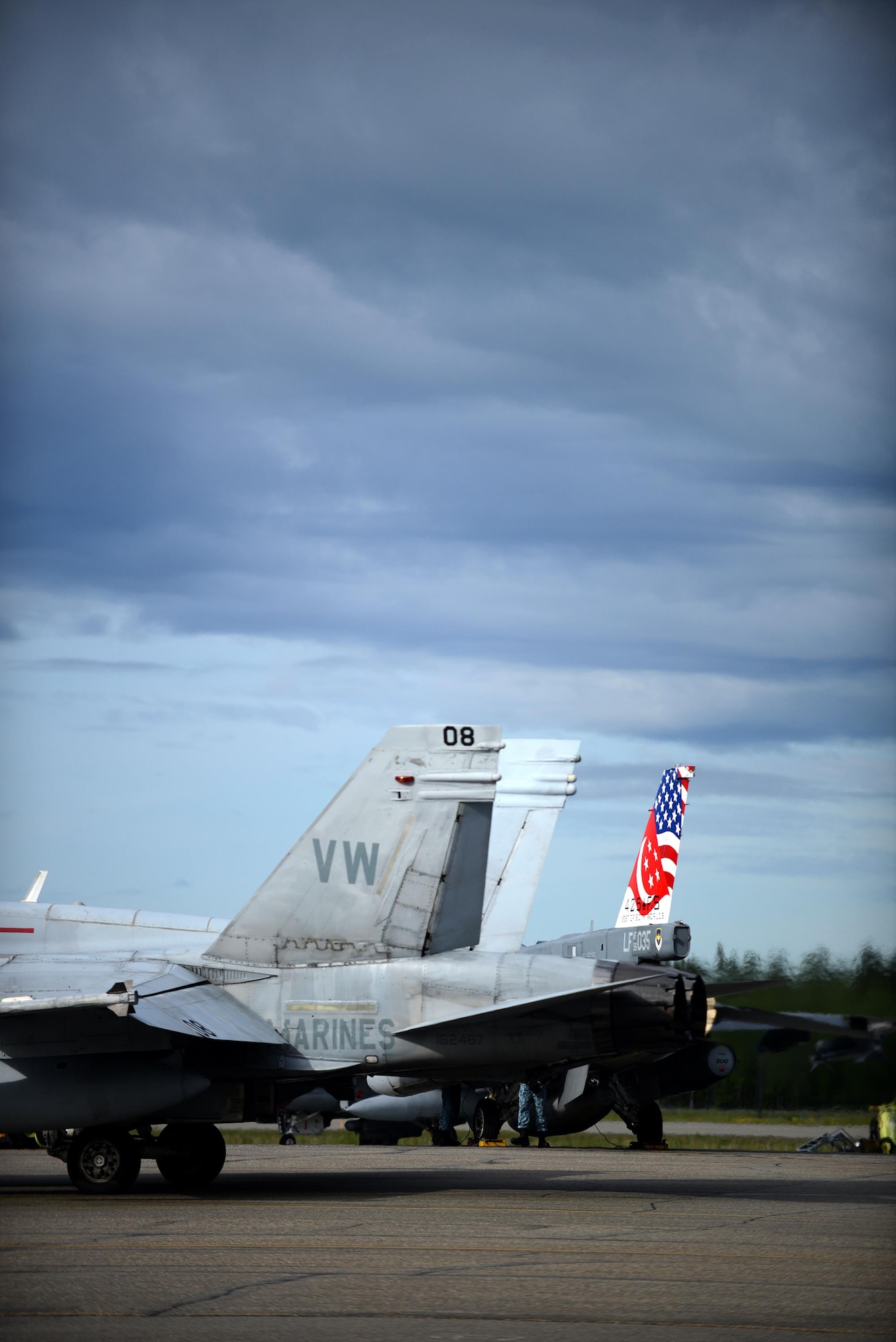 A U.S. Marine Corps F-18 Hornet assigned to Fixed Marine All-Weather Fighter Attack Squadron 242, Marine Corps Air Station Iwakuni, Japan, taxis past a Republic of Singapore Air Force F-16 Fighting Falcon, June 7, 2016, during RED FLAG-Alaska (RF-A) 16-2, at Eielson Air Force Base, Alaska. In addition to enabling joint and international units to work side-by-side, RF-A allows coalition forces to exchange tactics, techniques and procedures while improving interoperability. (U.S. Air Force photo by Tech. Sgt. Steven R. Doty)