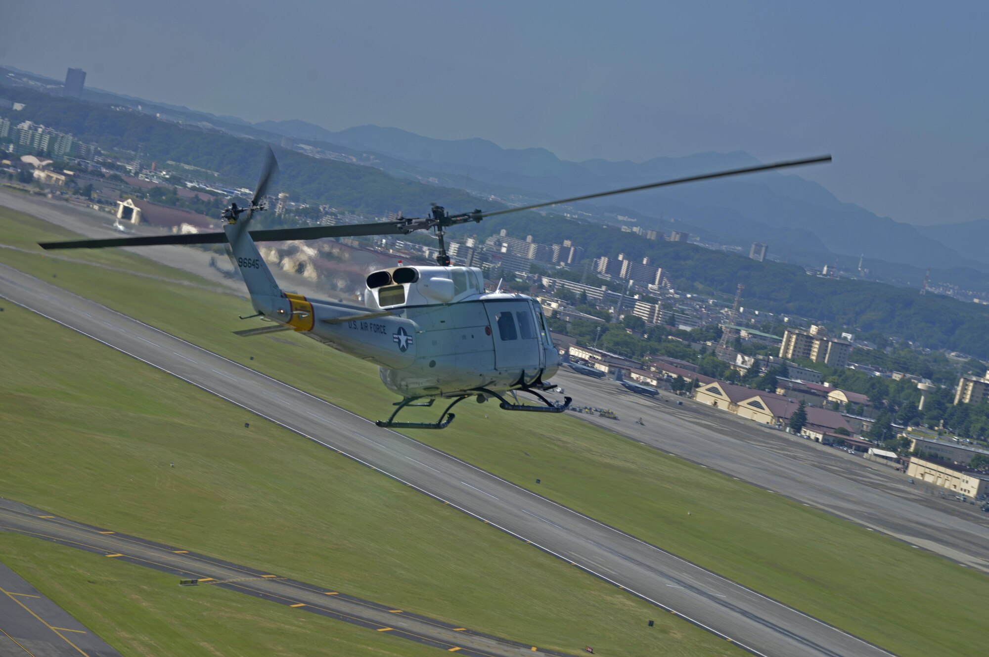 A UH-1N Iroquois with the 459th Airlift Squadron flies over Yokota Air Base, Japan, June 3, 2016. In peacetime, aircraft fly in formation to complete missions and training in which aircraft cannot transport all the people or cargo on its own. (U.S. Air Force photo by Senior Airman David Owsianka/Released)