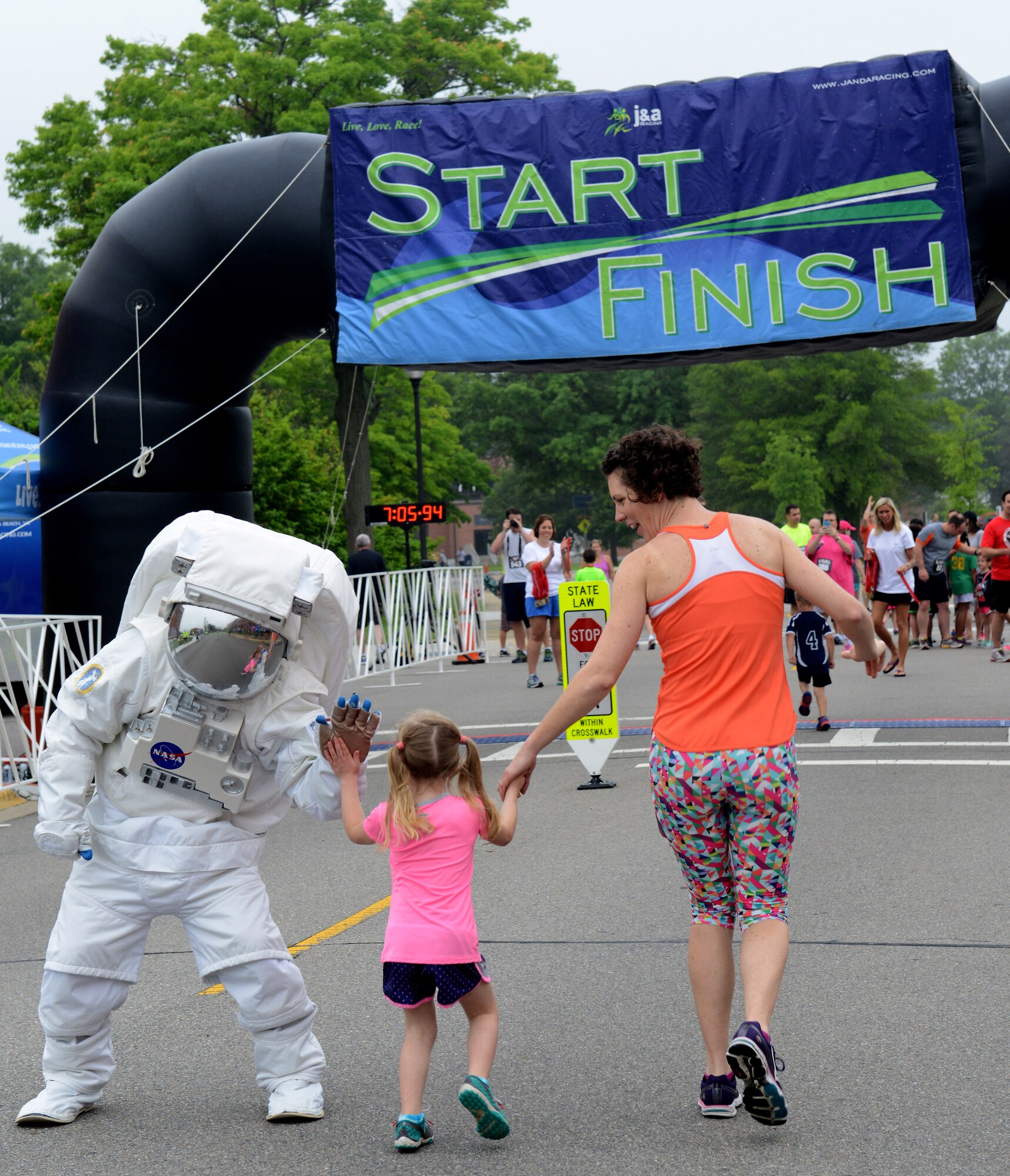 A NASA astronaut high-fives a child as she reaches the finish line of the Kids one-mile event during the NASA Langley Research Center Moonwalk and Run 5K at NASA LaRC, Va., June 4, 2016. This year’s event included more than 600 runners for the 5K and 100 children for the LaRC Kids run. (U.S. Air Force photo by Staff Sgt. Teresa J. Cleveland)