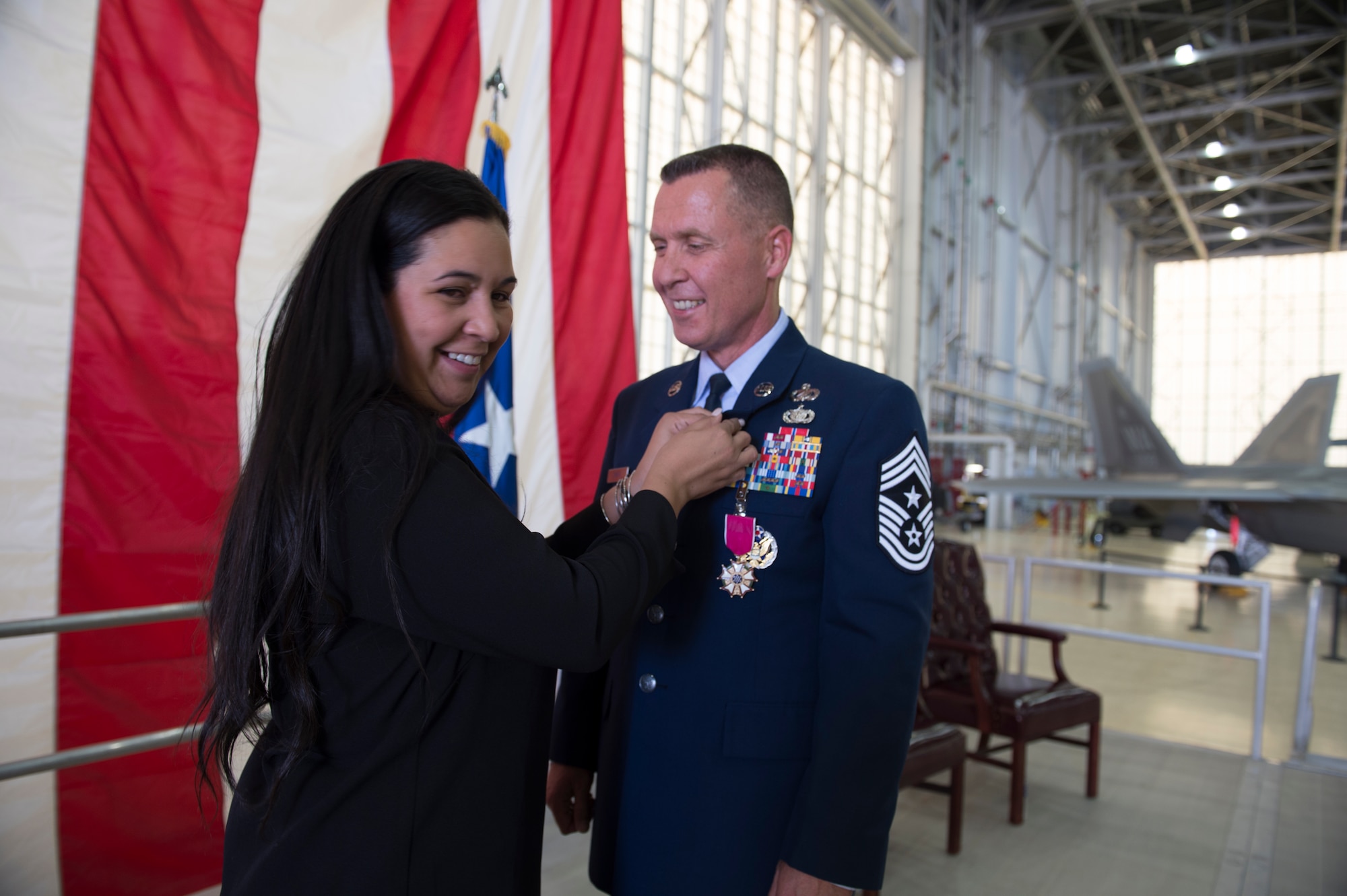 Leslie Smith, wife of Chief Master Sgt. David Smith pins a retirement pin on his lapel during Smith’s retirement ceremony June 3. the chief retired as command chief master sergeant for the 412th Test Wing. (U.S. Air Force photo by Joseph Pol Gocong.)