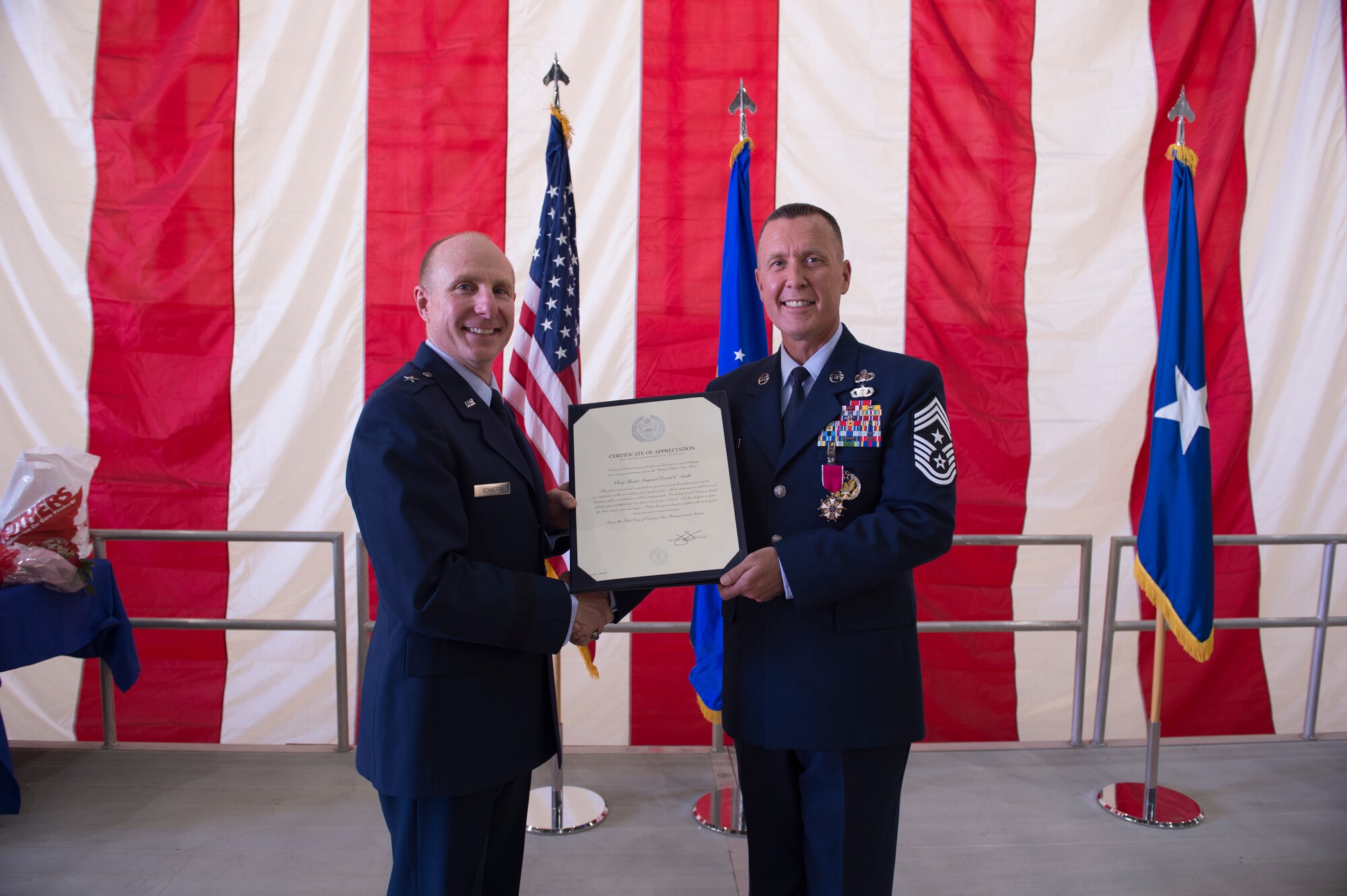 Brig. Gen. Carl Schaefer, 412th Test Wing commander, presents Chief Master Sgt. David Smith, 412th Test Wing command chief master sergeant, with his retirement certificate during a ceremony June 3. (U.S. Air Force photo by Joseph Pol Gocong.)
