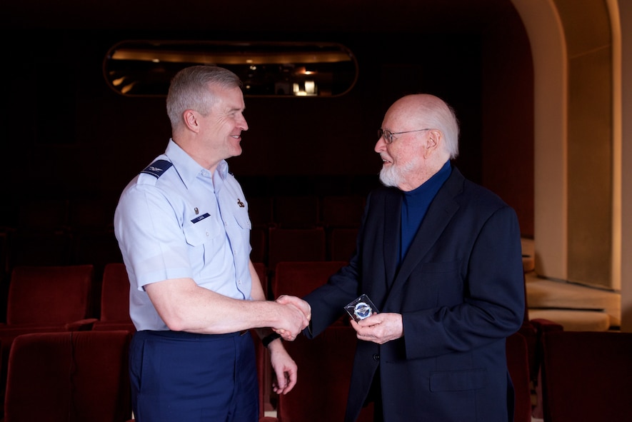 Col. Larry Lang, presents a band challenge coin to legendary conductor and composer John Williams at the conclusion of a recent interview with the former Airmen. Williams served in the U.S. Air Force as a pianist and brass player and also wrote and arranged as a secondary duty. (U.S. Air Force Photo/CMSgt Bob Kamholz)