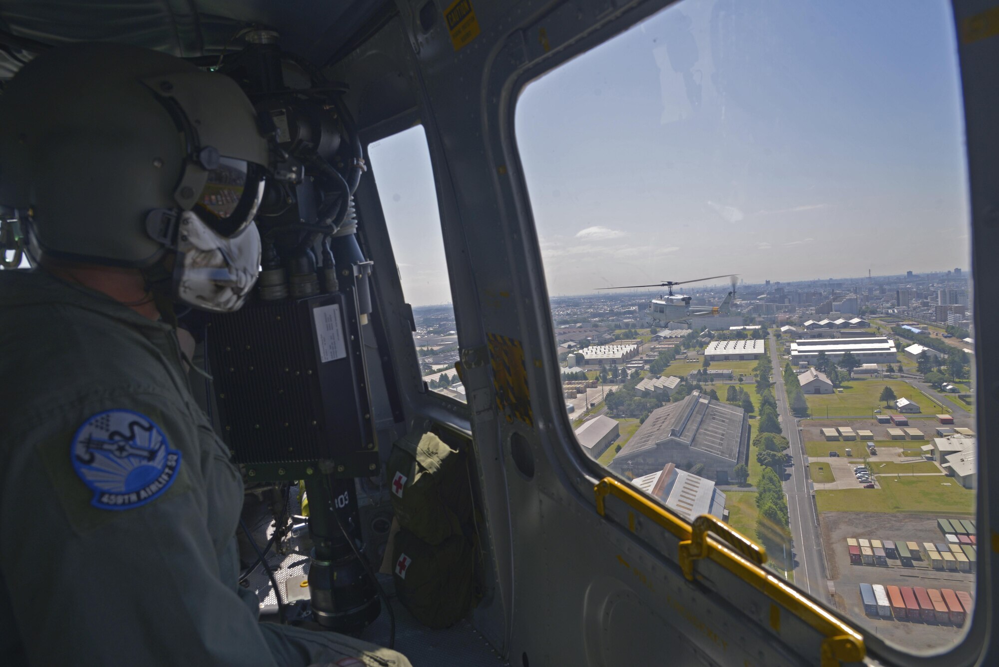 Tech. Sgt. Christopher Rector, 459th Airlift Squadron UH-1N flight engineer, views the Kanto Plains from a UH-1N Iroquois while flying over Japan, June 3, 2016. In peacetime, aircraft fly in formation to complete missions and training in which aircraft cannot transport all the people or cargo on its own. (U.S. Air Force photo by Senior Airman David Owsianka/Released)