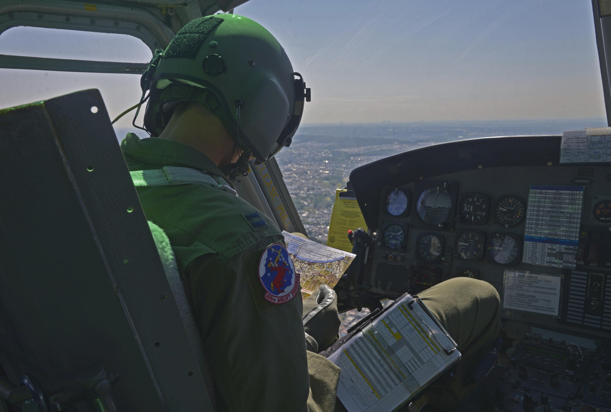 Capt. Daniel Trapani, 459th Airlift Squadron UH-1N instructor pilot, looks at a map while flying over Japan, June 3, 2016. In wartime operations, aircraft fly in formation to provide mutual support, such as, if one is engaged by the enemy, the other can provide back-up and call for reinforcements or rescue. (U.S. Air Force photo by Senior Airman David Owsianka/Released)