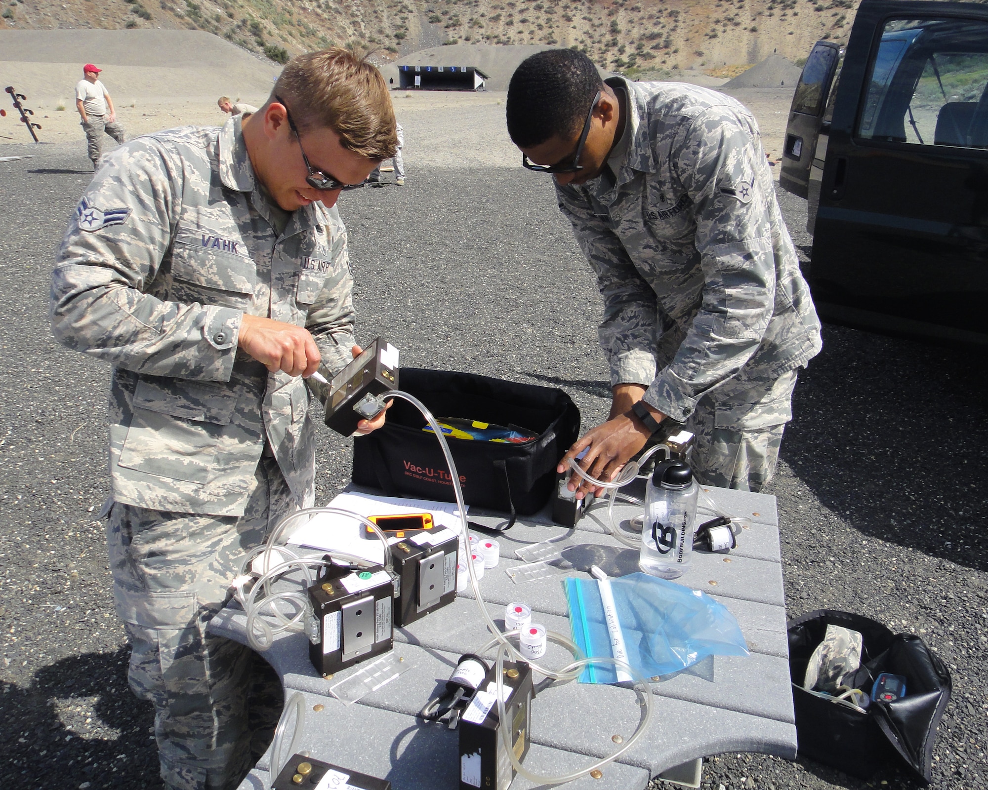 Airman 1st Class Ants Vahk and Airman Antione Van, both 92nd Aerospace Medicine Squadron bioenvironmental engineers, prepare air sampling pumps May 25, 2016 at the Grand Coulee Damn shooting range. The air samples collected were of copper dust, fumes and lead during a heavy weapons firing. “We’ll do an air sampling, send the samples to the lab and then wait for the results to let us know if we need to take any further precautions,” Vahk said.  (Courtesy Photo)