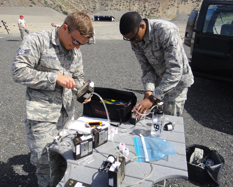 Airman 1st Class Ants Vahk and Airman Antione Van, both 92nd Aerospace Medicine Squadron bioenvironmental engineers, prepare air sampling pumps May 25, 2016 at the Grand Coulee Damn shooting range. The air samples collected were of copper dust, fumes and lead during a heavy weapons firing. “We’ll do an air sampling, send the samples to the lab and then wait for the results to let us know if we need to take any further precautions,” Vahk said.  (Courtesy Photo)