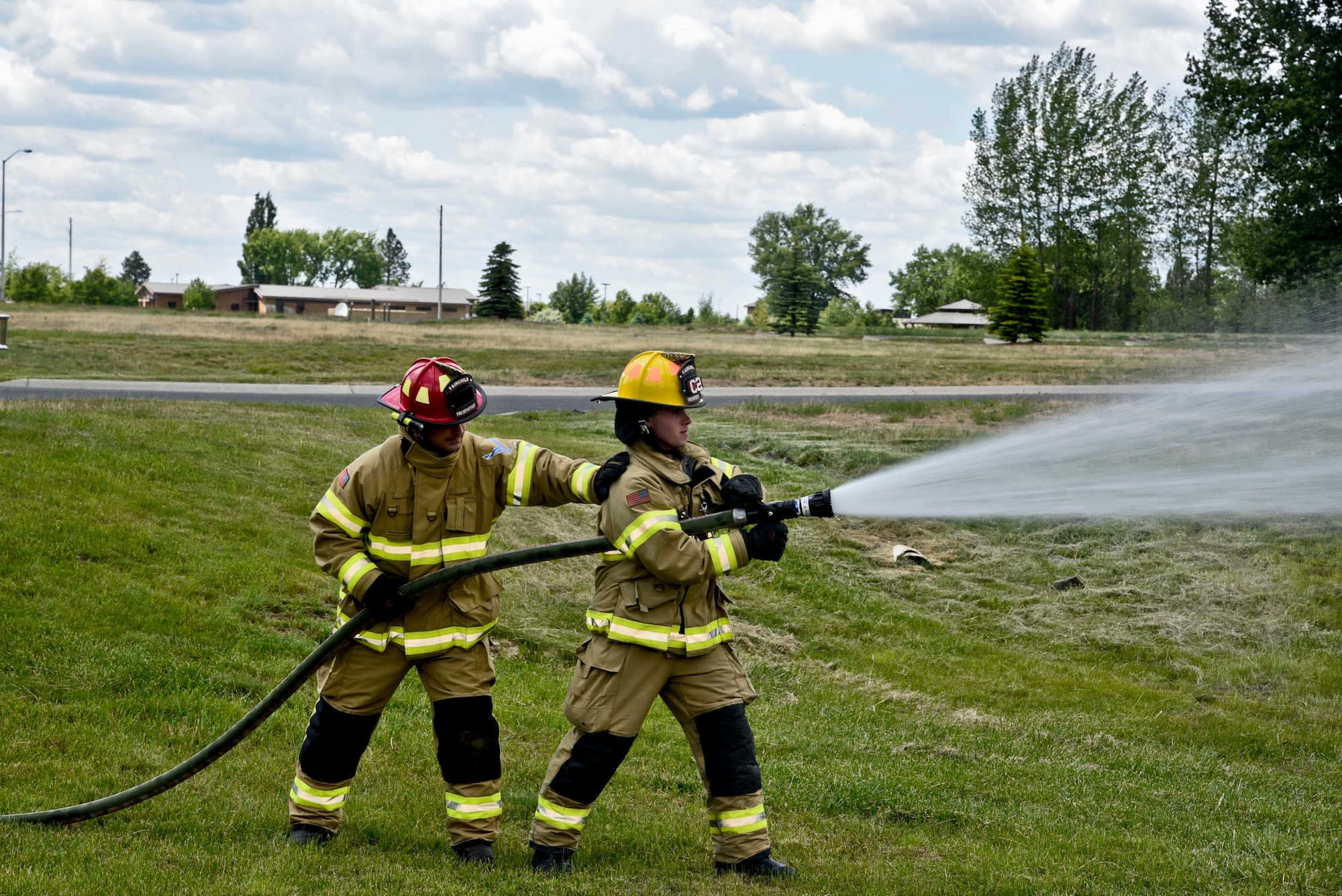 Staff Sgt. Patrick Guthrie, 92nd Civil Engineer Squadron firefighter crew chief, supports Airman 1st Class Shawn Mercer, 92nd CES firefighter, while demonstrating how to properly use a fire hose May 25, 2016, at Fairchild Air Force Base, Wash. According to Mercer, knowing how to control the path of the fire and protecting the surrounding buildings, is one of the most important skills a firefighter possesses. (U.S. Air Force photo/Airman 1st Class Taylor Shelton)