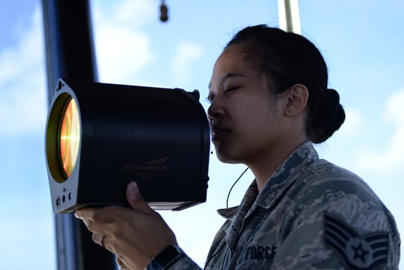 Staff Sgt. Tiffany Degracia, 36th Operations Support Squadron air traffic controller, signals a vehicle on the flightline with a light gun June 2, 2016, at Andersen Air Force Base, Guam. The light guns flash red, white or green lights in various patterns to signal how to proceed when communication with an aircraft or vehicle is lost. (U.S. Air Force photo by Airman 1st Class Jacob Skovo)