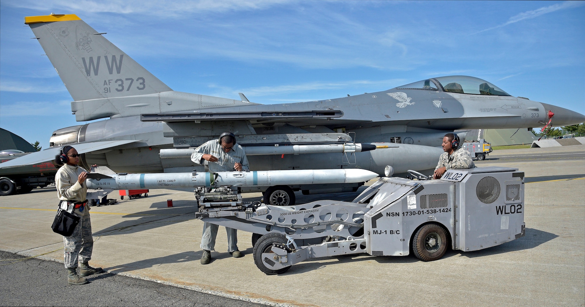 U.S. Air Force Airman 1st Class Lanell Lewis (left) and Staff Sgt. Miles Smith (center) prepare an AIM-120 advanced medium-range air-to-air missile for loading onto an F-16 Fighting Falcon via an MHU-83 lift truck, driven by Senior Airman Mitchell Gibson, right, at Misawa Air Base, Japan, June 6, 2016. Smith, Gibson and Lewis are armament systems specialists with the 35th Aircraft Maintenance Squadron, who participated in a three-day surge, sharping their proficiency in aircraft maintenance and wartime operations. (U.S. Air Force photo by Senior Airman Deana Heitzman)