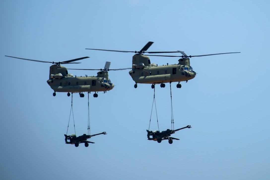 Two Army CH-47 Chinook helicopters slingload M777A2 howitzers during exercise Crescent Reach 16 at Fort Bragg, N.C., May 26, 2016. The howitzer crews are assigned to the 82nd Airborne Division’s 3rd Battalion, 319th Airborne Field Artillery Regiment. The annual exercise evaluates the base's abilities in a large-scale aircraft formation while deploying airmen and cargo in response to a simulated crisis abroad. Air Force photo by Airman 1st Class Sean Carnes