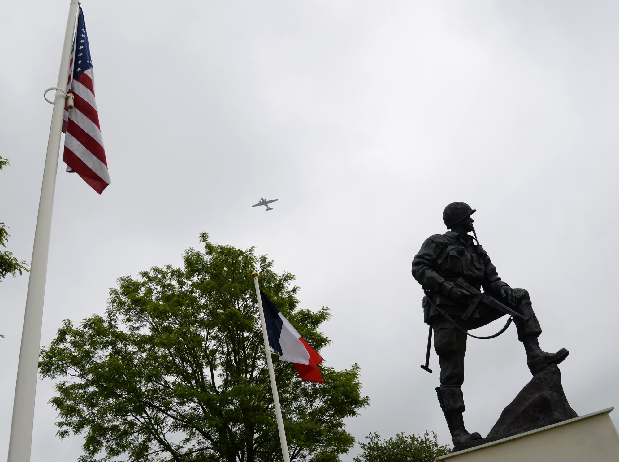 NATO allied nations perform flyovers in preparation for air drops scheduled for June 5, 2016 over Normandy, France. The statue of an American soldier, named Iron Mike, stands at the top of Memorial Park in Sainte-Mère-Église. Memorial Park is dedicated to American airborne troops who lost their lives during the airdrops on D-Day. During World War II, the Battle of Normandy began on D-Day, June 6, 1944, when approximately 156,000 American, British and Canadian forces landed on five beaches along a 50-mile stretch of the coast of France’s Normandy region. (U.S. Air Force photo by Senior Airman Justine Rho/Released)