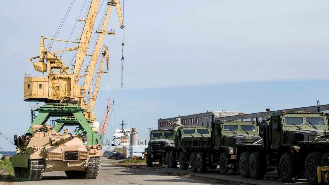 Abrams tank travels alongside a fleet of 7-ton trucks after being offloaded from ship in preparation of Exercise Saber Strike 16 in Riga, Latvia, June 4, 2016. Exercise Saber Strike is an annual combined-joint exercise in the Baltic region. The combined training prepares allies and partners to respond more to regional crises and meet their own security needs by improving the security of borders and countering threats. 