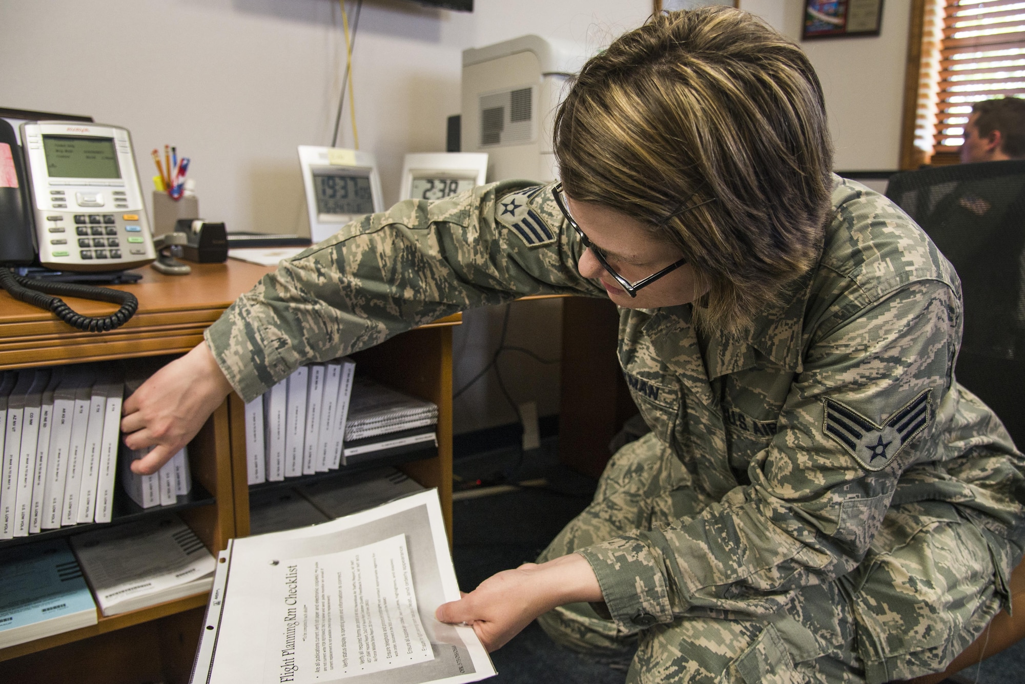 Senior Airman Laura Hackman, 375th Operational Support Squadron airfield managament shift leader, goes over the flight planning checklist in the flight planning room at Scott Air Force Base, Illinois on May 24, 2016. the FPR is where the transient aircrew can access paper or digital flight information publications, air navigation charts or relax between flights. (U.S. Air Force Photo by Airman Daniel Garcia)