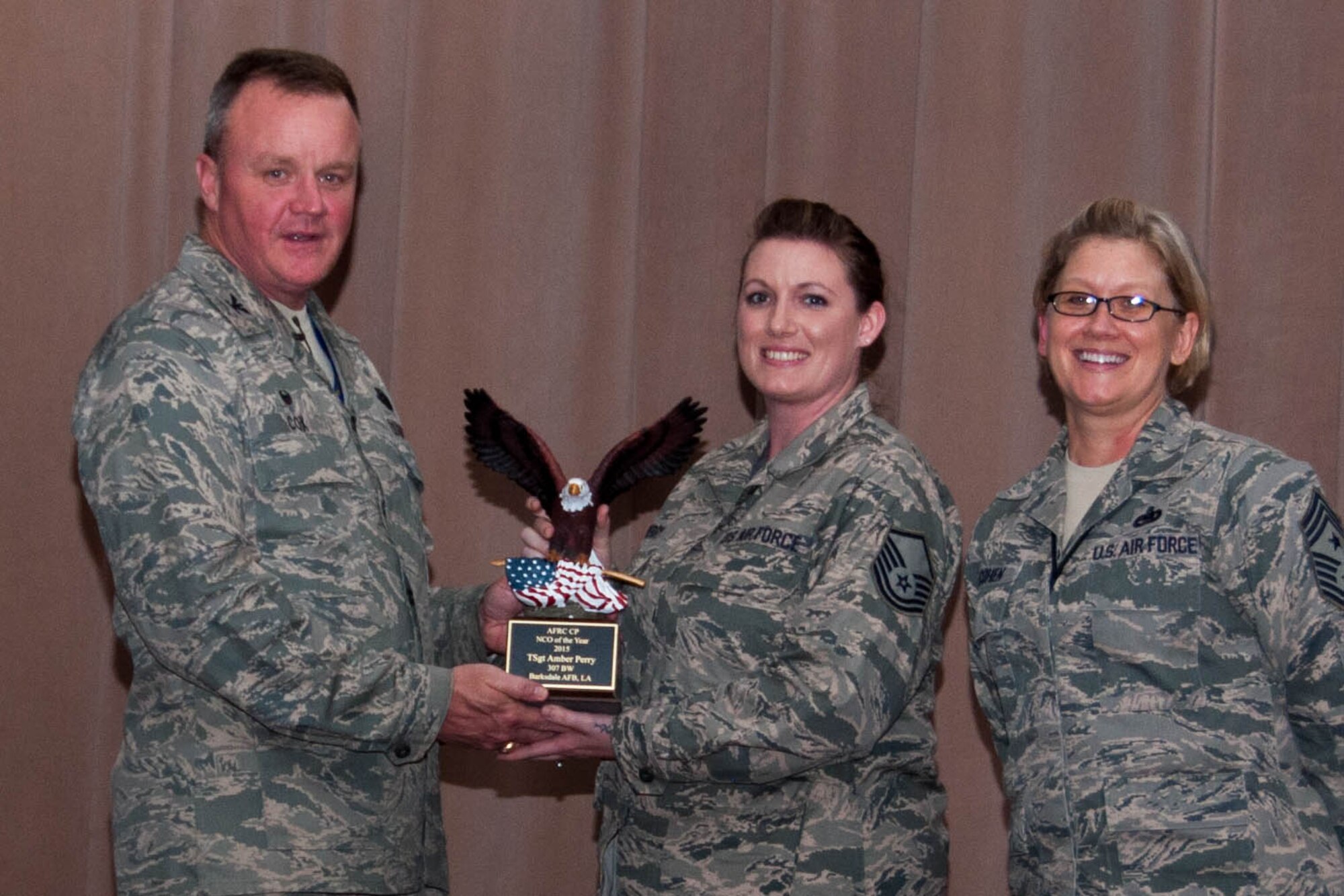 U.S. Air Force Master Sgt. Amber Perry, 307th Bomb Wing, is awarded the 2015 AFRC Command Post Noncommissioned Officer of the Year during Commander’s Call on Barksdale Air Force Base, La., June 5, 2016. Presenting Perry with a trophy is the 307th Bomb Wing Commander, Col. Bruce Cox, and the 307th Bomb Wing Command Chief, Chief Master Sgt. Shelley Cohen. (U.S. Air Force photo by Master Sgt. Laura Siebert/Released)