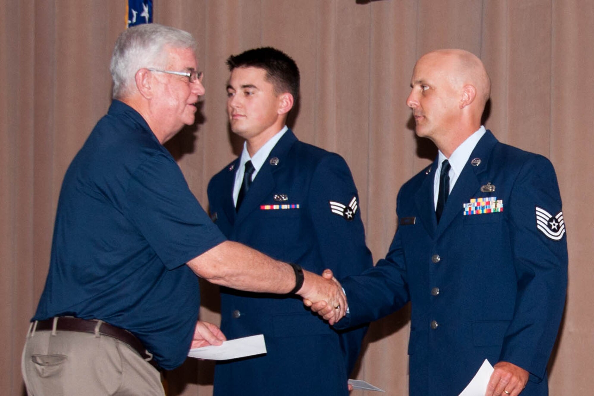 Dale Bickham, representing Barksdale Federal Credit Union, shakes hands with U.S. Air Force Tech. Sgt. Ted Daigle, 307th Bomb Wing Public Affairs, during a Commander’s Call on June 5 at Barksdale Air Force Base, La. Daigle is being congratulated by the civic leader for being awarded the 307th Bomb Wing Noncommissioned Officer of the Quarter for the first quarter. (U.S. Air Force photo by Master Sgt. Laura Siebert/Released)