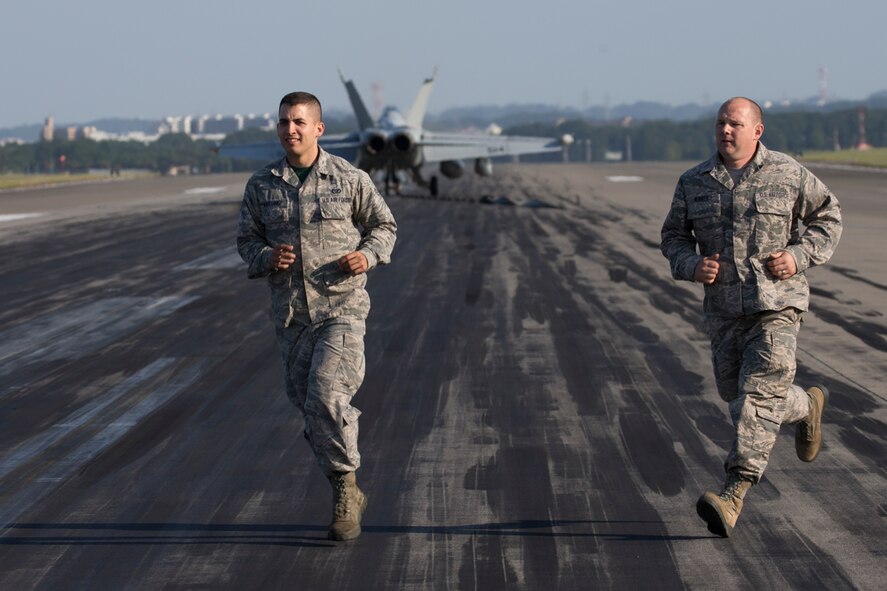 Senior Airman David Martinez, 374th Civil Engineer Squadron electrical power productions technician, and Senior Airman Timothy Wunker, 919th Special Operations Civil Engineer Squadron electrical power productions technician, run across the flightline during an annual certification test of an aircraft arresting system at Yokota Air Base, Japan, June 3, 2016. The system went through an annual certification test with a Navy EA-18G Growler to ensure its operability following installation by the 374 CES power productions shop. (U.S. Air Force photo by Yasuo Osakabe/Released)