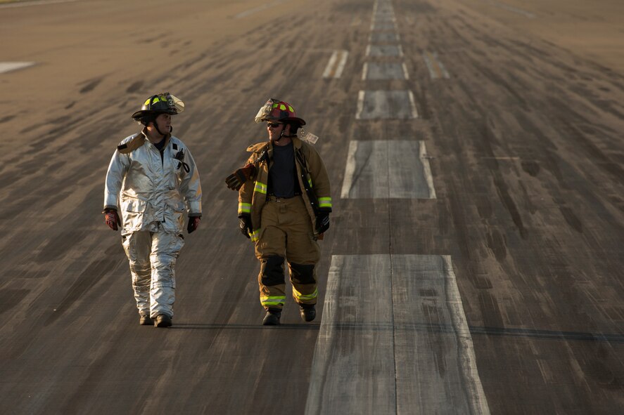 (Right to left) Staff Sgt. Colin Huffaker and Senior Airman Kirk Ebel, 374th Civil Engineer Squadron firefighters, walk the flightline after completing a certification test for an aircraft arresting system at Yokota Air Base, Japan, June 3, 2016.  The 374th Civil Engineer Squadron power productions shop and fire department and 374th Operations Support Squadron airfield management flight are responsible for testing the system annually. (U.S. Air Force photo by Yasuo Osakabe/Released)   