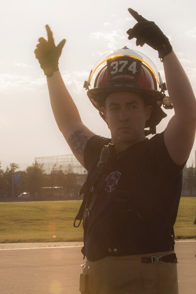 Staff Sgt. Richard Austin, 374th Civil Engineer Squadron fire department crew chief, signals for his team members to reel in the nylon tape from the aircraft arresting system at Yokota Air Base, Japan, June 3, 2016. The 374 CES and 374th Operations Support Squadron airfield management flight are responsible for testing the system annually. (U.S. Air Force photo by Senior Airman David C. Danford/Released)