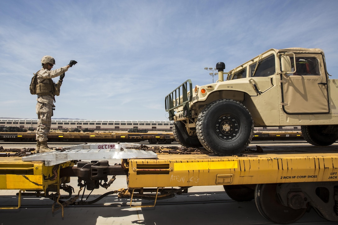 Marine Corps Pfc. Andrew Eckhardt guides a humvee onto rail cars while participating in rail operations training at Marine Corps Logistics Base Barstow, Calif., June 7, 2016. Eckhardt practiced preparing vehicles for rail transportation while wearing full combat gear in the harsh Mojave Desert heat to prepare for future operations. Eckhardt is assigned to Combat Logistics Battalion 7. Marine Corps photo by Carlos Guerra