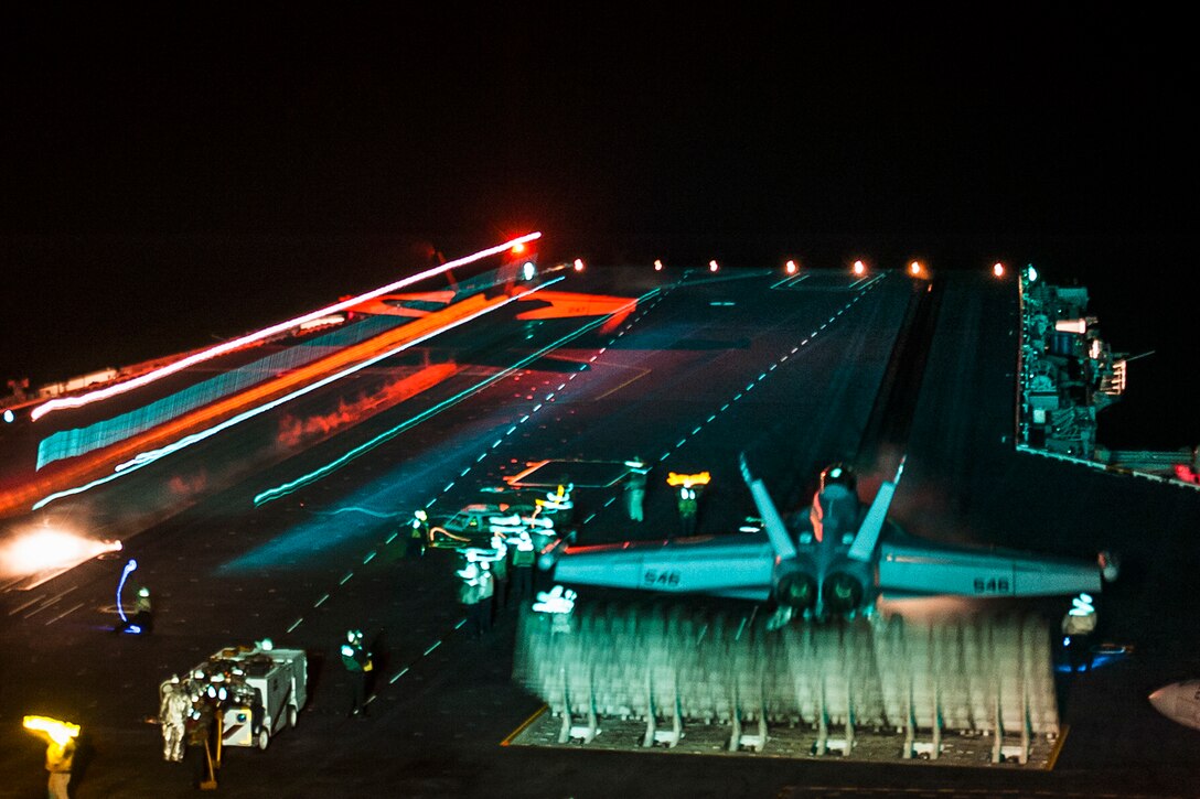 An F/A-18E aircraft assigned to Strike Fighter Squadron, left, launches from the USS Carl Vinson flight deck in the Pacific Ocean, June 4, 2016, during night flight operations. At the same time, an EA-18G Growler assigned to Electronic Attack Squadron taxis onto a catapult. The ship is conducting command assessment of readiness and training off Southern California. Navy Photo by Seaman Apprentice Daniel P. Jackson Norgart