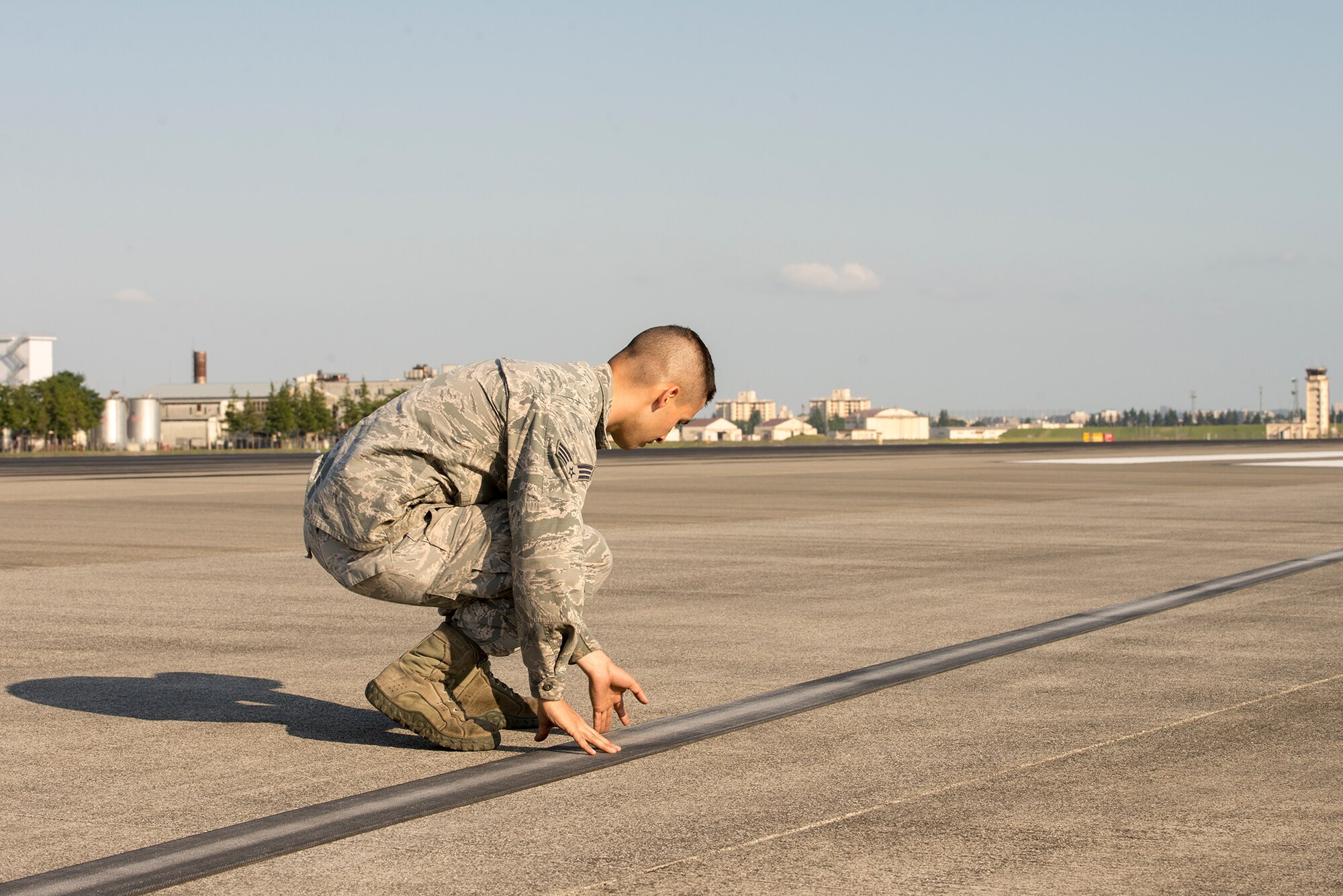 Senior Airman David Martinez, 374th Civil Engineer Squadron electrical power production technician, checks the nylon tape for the aircraft arresting system at Yokota Air Base, Japan, June 3, 2016. The tape is stored on reels connected to AAS absorbers secured on both sides of the runway and has a 1,200-foot runout. (U.S. Air Force photo by Senior Airman David C. Danford/Released)