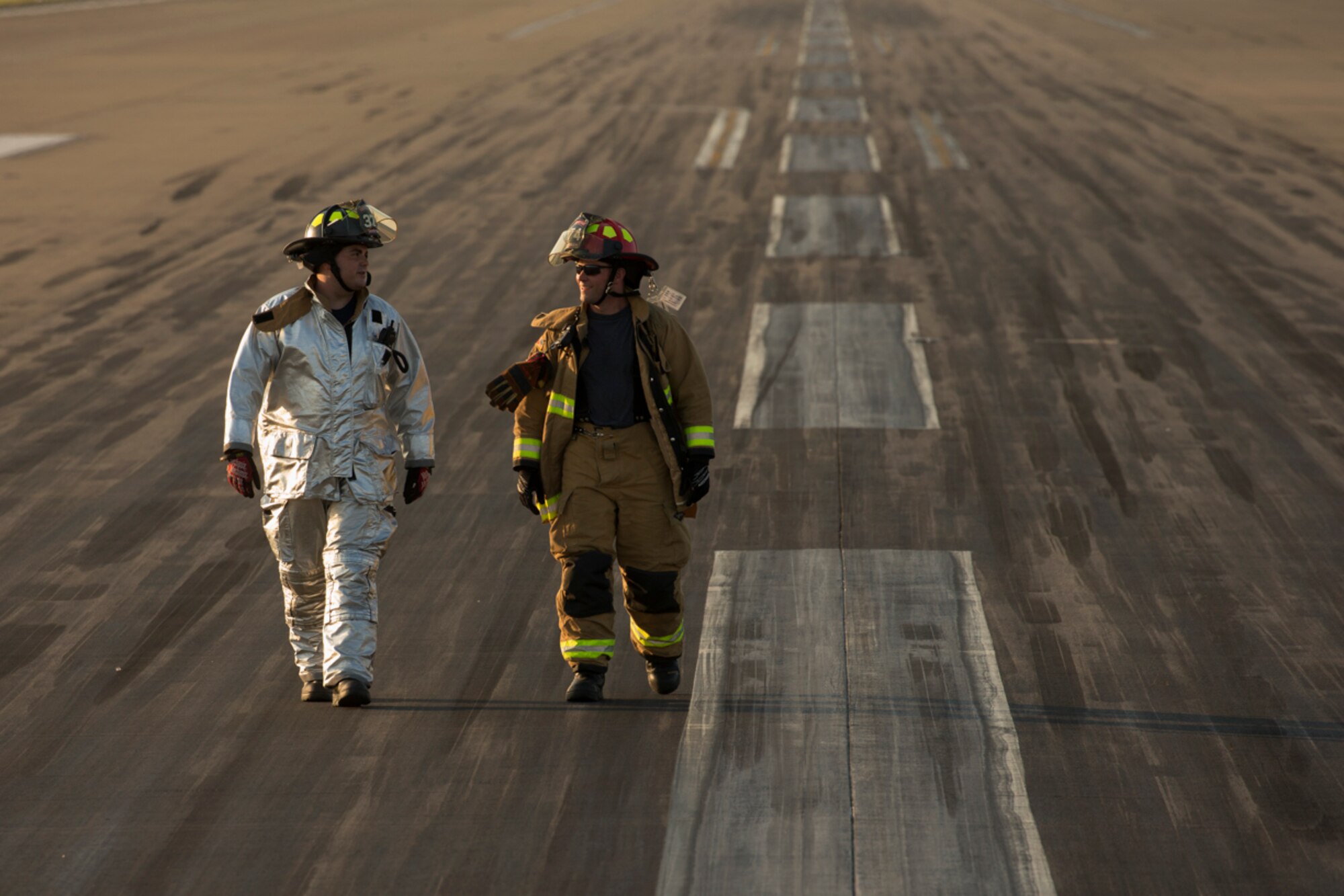 (Right to left) Staff Sgt. Colin Huffaker and Senior Airman Kirk Ebel, 374th Civil Engineer Squadron firefighters, walk the flightline after completing a certification test for an aircraft arresting system at Yokota Air Base, Japan, June 3, 2016.  The 374th Civil Engineer Squadron power productions shop and fire department and 374th Operations Support Squadron airfield management flight are responsible for testing the system annually. (U.S. Air Force photo by Yasuo Osakabe/Released)