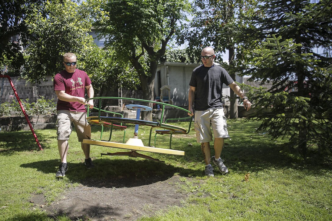 RPSA Alexander Varner, religious personnel specialist with Special Purpose Marine Air-Ground Task Force Crisis Response-Africa, and Staff Sgt. Gary Dow, a theater security cooperation logistics chief, move a merry-go-round in the courtyard at Marie Ausiliatrice School in Catania, Italy, June 7, 2016.  Marines volunteered their time performing general site maintenance and building an above ground pool in preparation for a summer camp at the orphanage.  (U.S. Marine Corps photo by Cpl. Alexander Mitchell/released)