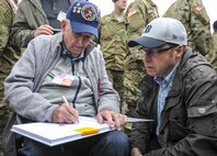 Cliff Goodall, a World War II veteran, signs an autograph after a memorial ceremony June 4, 2016, in Angoville-au-Plain, France. The memorial ceremony was in honor of Kenneth Moore and Robert Wright, medics with the 101st Airborne Division during World War II, who provided medical care to allies and enemies alike at the Angoville-au-Plain church in June 1944. (U.S. Air Force photo by Staff Sgt. Timothy Moore)
