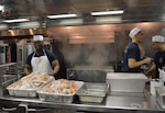 After the Navy took ownership of the USS Zumwalt (DDG 1000), the supply department works to feed sailors aboard the destroyer May 20 in Bath, Maine. The Zumwalt’s inaugural dinner included lobster tail, crab and filet mignon.