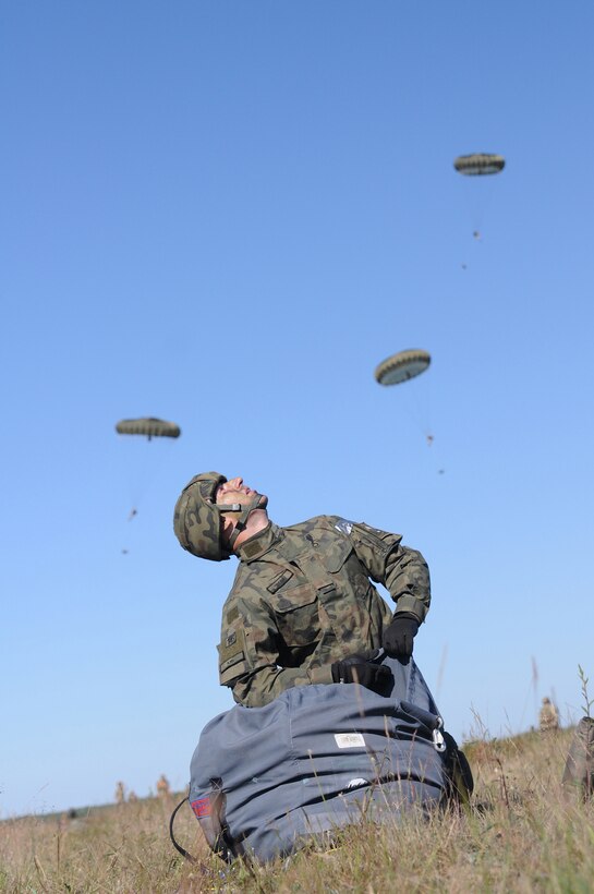 A Polish paratrooper reacts to incoming paratroopers at the drop zone in Torun, Poland, for Exercise Anakonda 2016, a Polish-led, multinational exercise running from June 7-17, involves approximately 25,000 participants from more than 20 nations and is a premier training event for U.S. Army Europe.