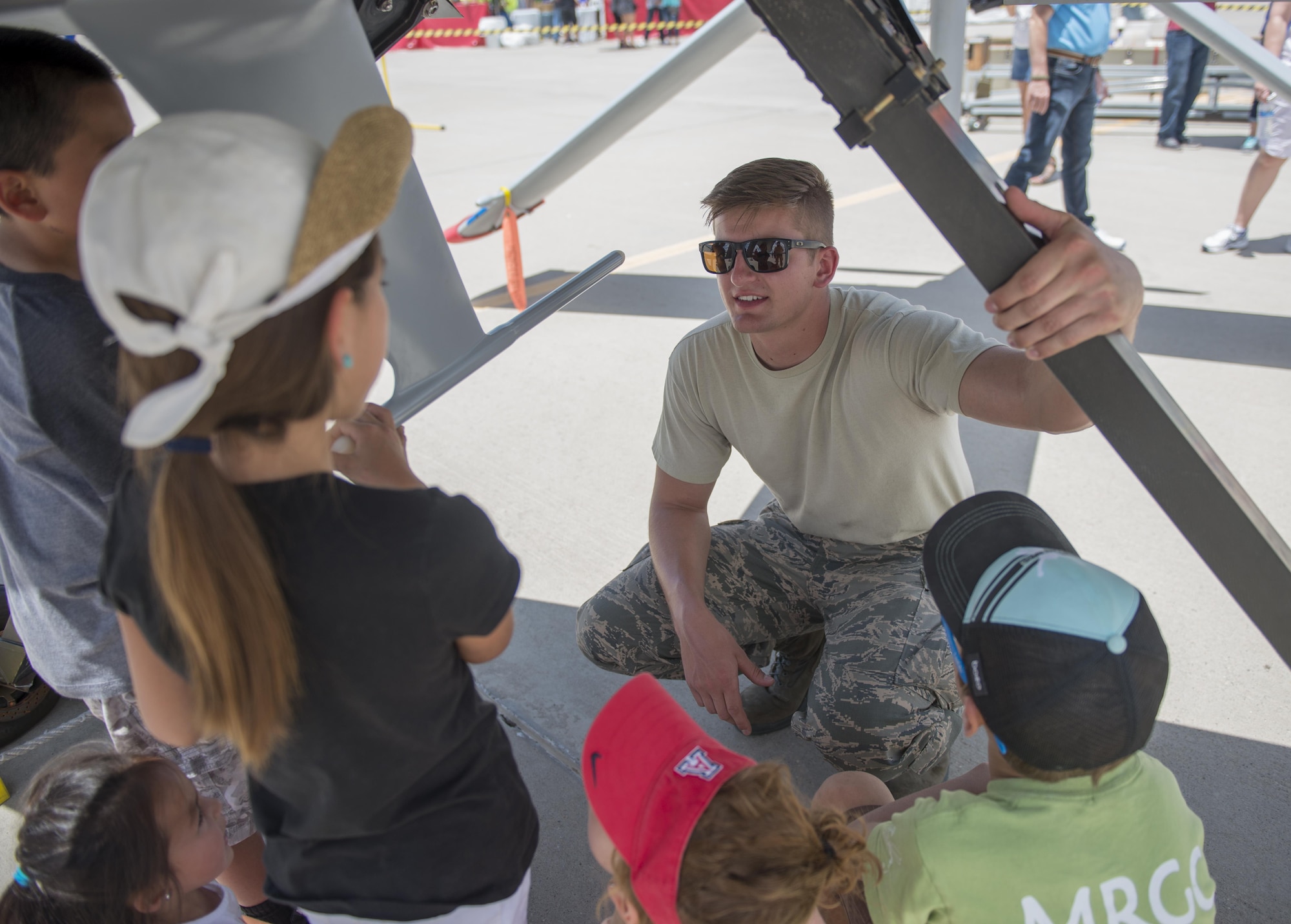 Senior Airman Alex, a 9th Aircraft Maintenance Unit crew chief at Holloman Air Force Base, N.M., tells children about some of the components found underneath an MQ-1 at the Kirtland AFB Open House on June 5. Over 50,000 people visited the Kirtland AFB Air Show on June 4 and 5. Holloman Airmen had the opportunity to display an MQ-1 Predator and answer questions visitors had about RPAs and their mission at Holloman. (Last names are being withheld due to operational requirements. U.S. Air Force photo by Airman 1st Class Randahl J. Jenson) 